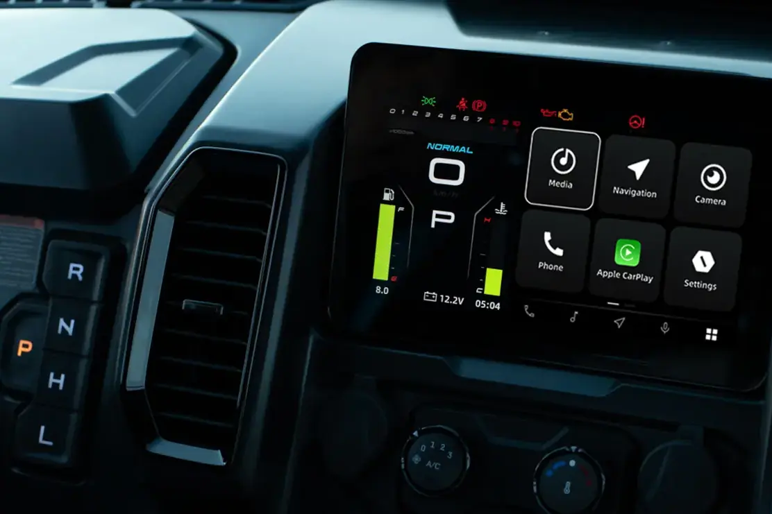 Close-up of a car's digital dashboard display showcasing innovative technology with gear shift indicators, system status, and touchscreen options for media, navigation, phone, Apple CarPlay, and settings—features now influencing ATVs and UTVs.