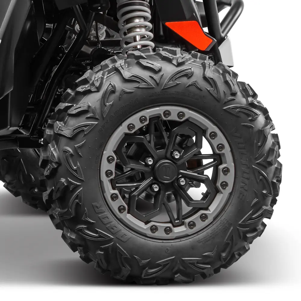 ZFORCE 950 feature 3 Close-up view of a rugged zforce 950 sport 4 off-road vehicle tire and black alloy wheel with visible suspension spring and part of the vehicle's body.