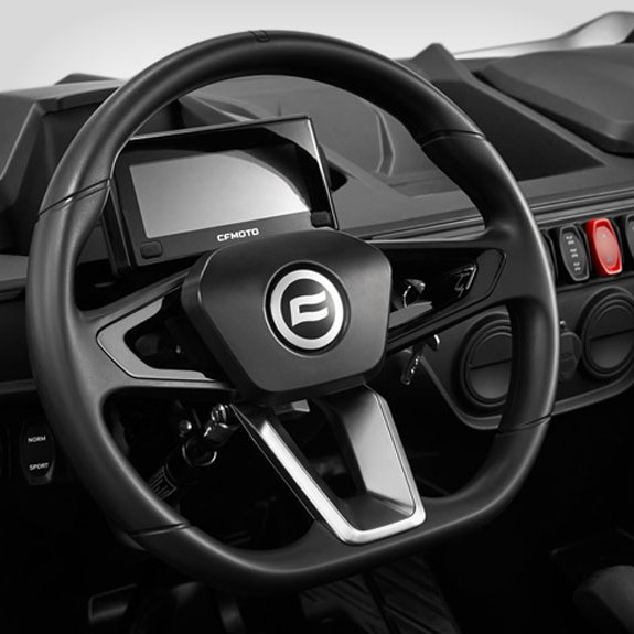 sxs_zforce-950-sport_fh-2 Close-up of a zforce 950 sport steering wheel with a digital display behind it and various control buttons on the dashboard.