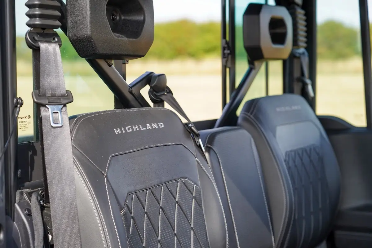 Close-up view of two black "Highland" seats with safety belts inside a UFORCE U10 PRO HIGHLAND vehicle, featuring headrests and a window in the background.