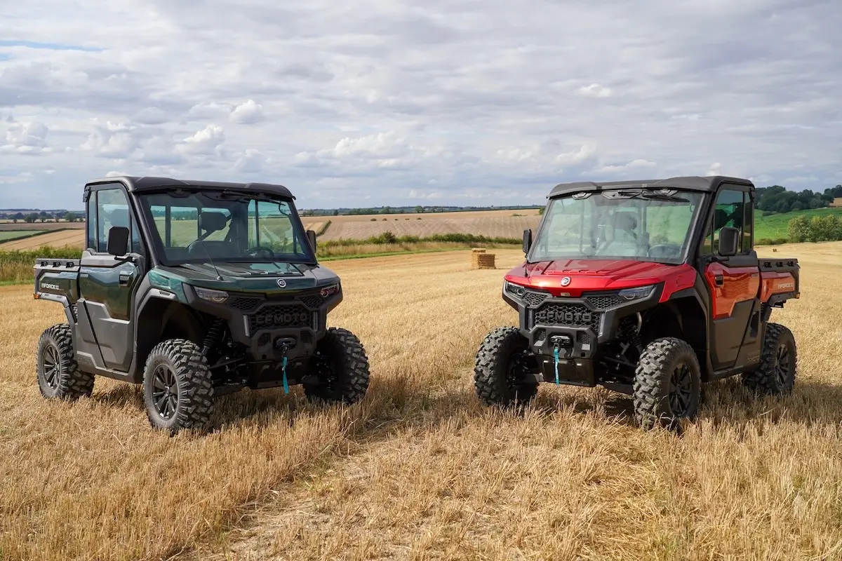 Two off-road utility vehicles, including the UFORCE U10 PRO HIGHLAND in black and a red model, are parked in a harvested field under a cloudy sky.