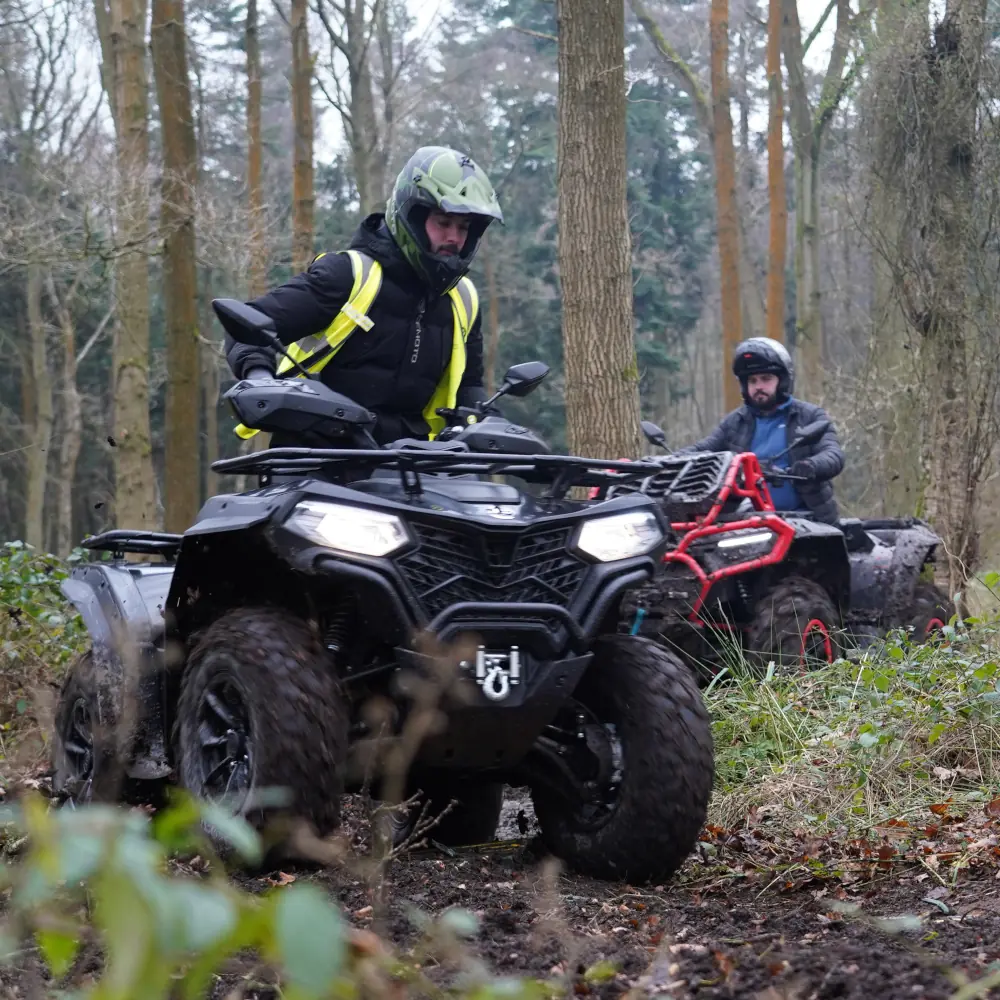commercial fleet vehicles Two people ride a fleet of all-terrain vehicles through a muddy forest trail, wearing helmets and outdoor kit.