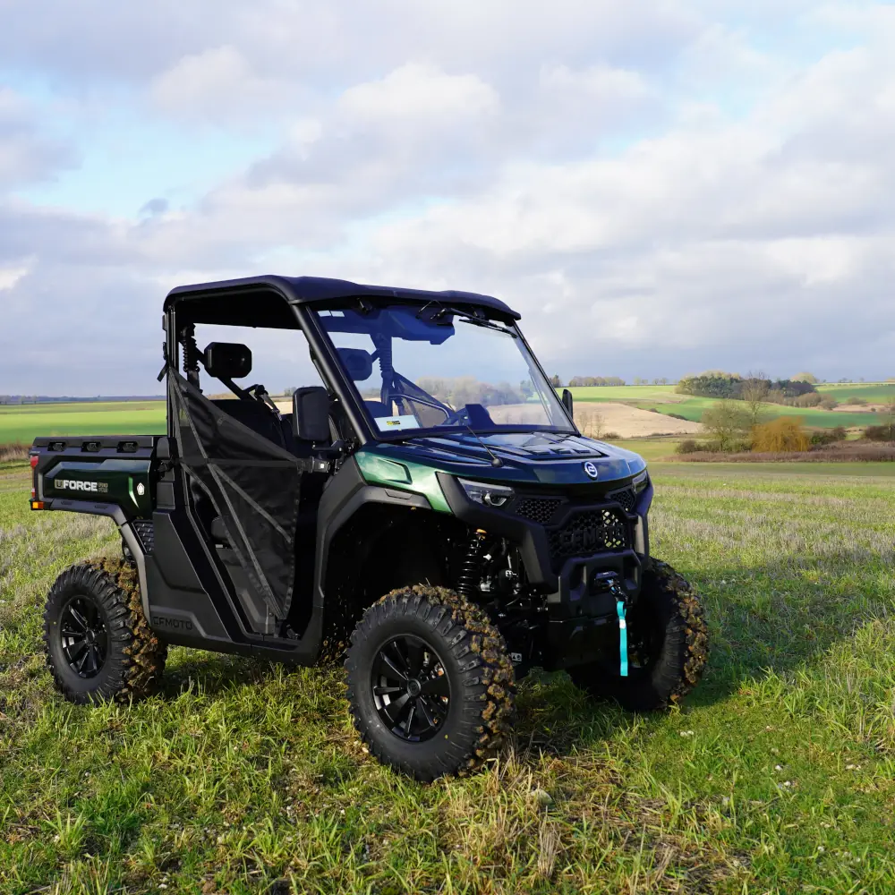 fleet utvs A black and green utility terrain vehicle (UTV) from the fleet is parked on a grassy field, set against rolling hills and a cloudy sky in the background.