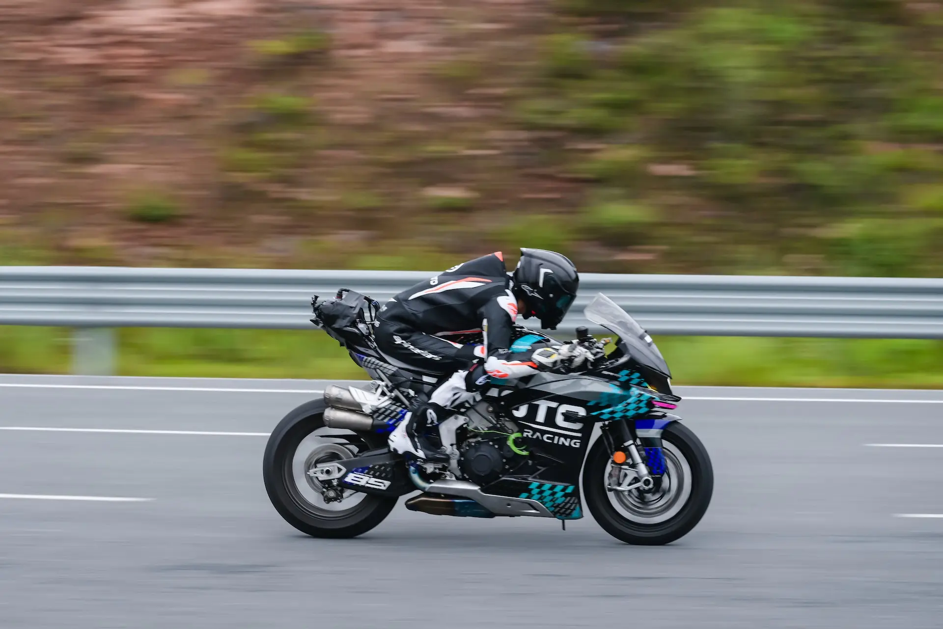 A motorcyclist in full racing gear rides a CFMOTO V4 SR-RR at top speed—reaching up to 315.82 km/h—on a tarmacked road with a metal crash barrier and greenery in the background.