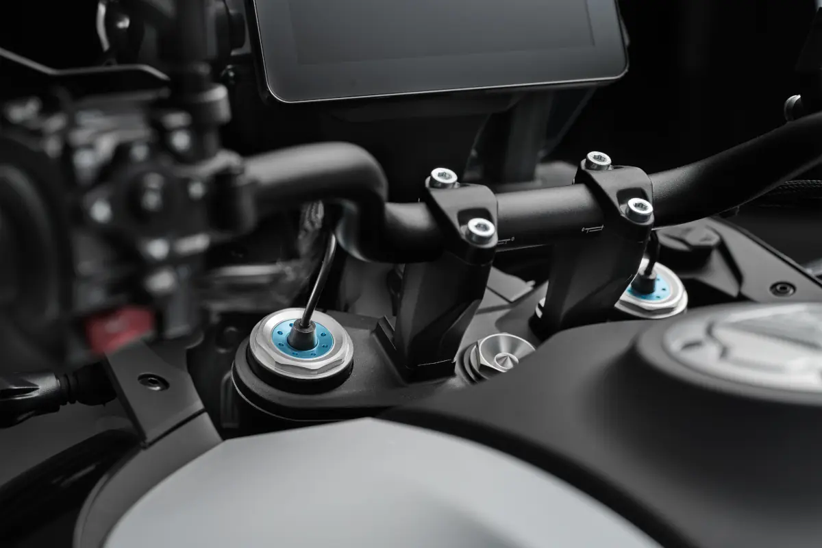 Close-up of a CFMOTO 800MT-ES tech motorcycle handlebar and dashboard, showing the advanced control panel, grips, and mounting hardware with striking blue accents.