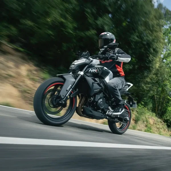 450nk a2 licence motorcycle A motorcyclist wearing a helmet and jacket rides a black CF Moto NK, one of the popular A2 motorbikes, on a tarmac road with trees in the background.